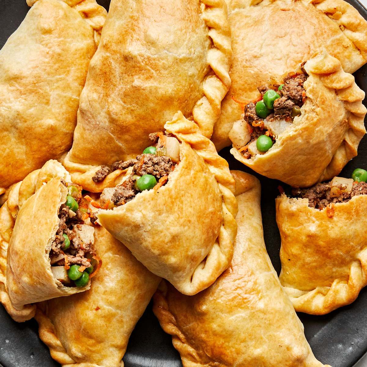 Beef empanadas with pea and carrot filling on a black plate